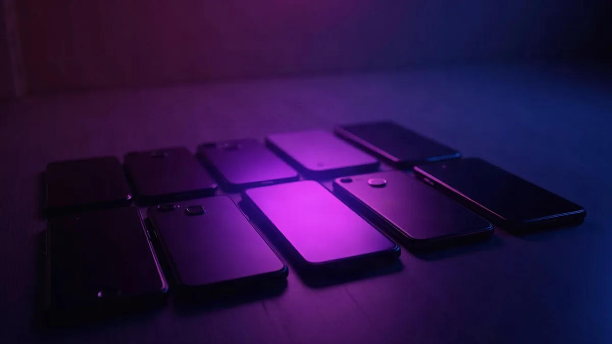 Mehrere aufgereihte Smartphones, ein violetter Scheinwerfer auf dem mittleren (Illustration zum Artikel)